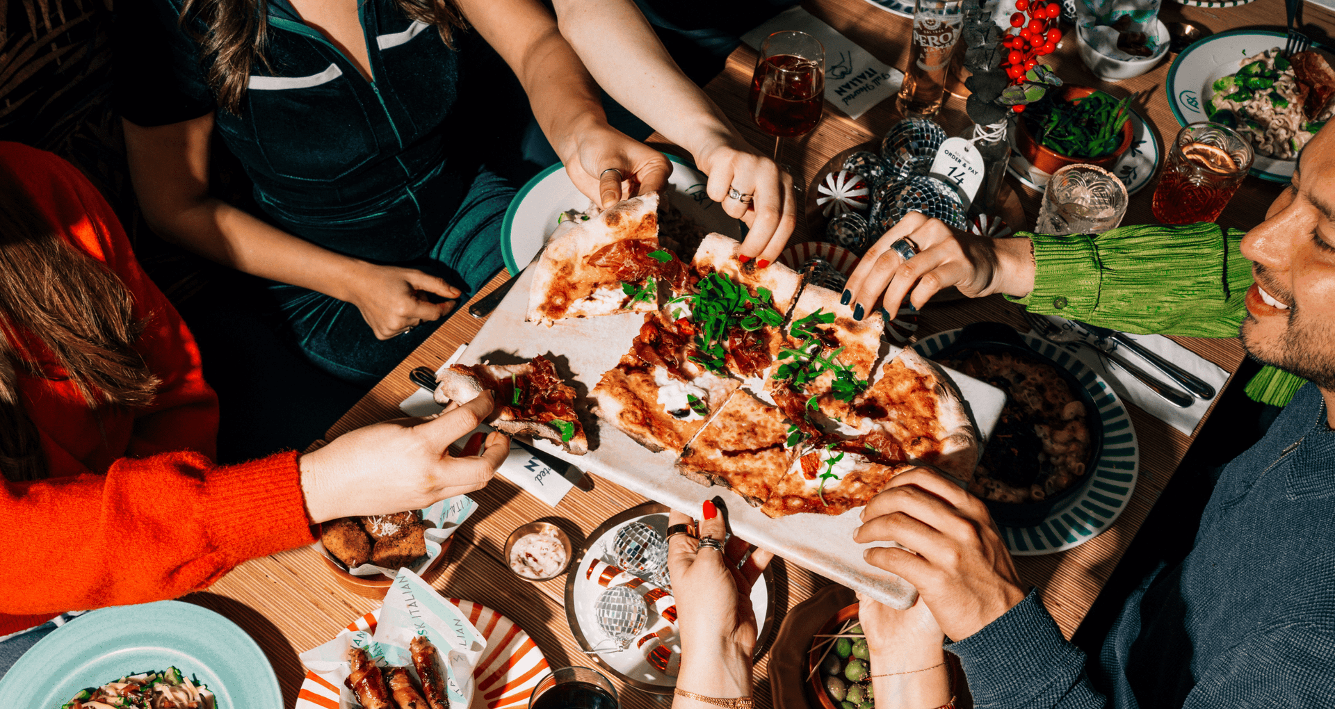 A group of people enjoying a Christmas party at ASK Italian restaurants, with everyone tucking into a festive special pizza.