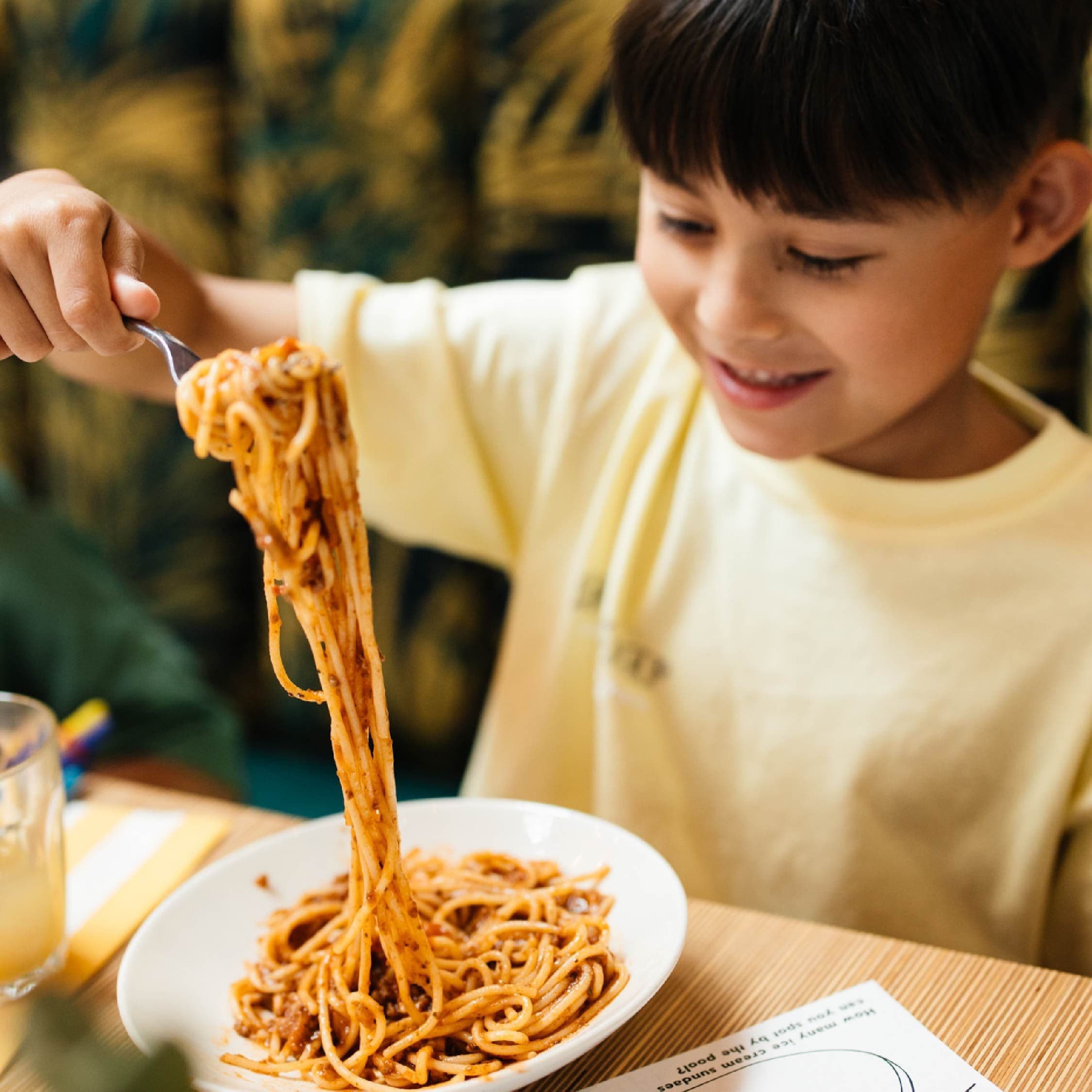A child eating a large forkful of pasta