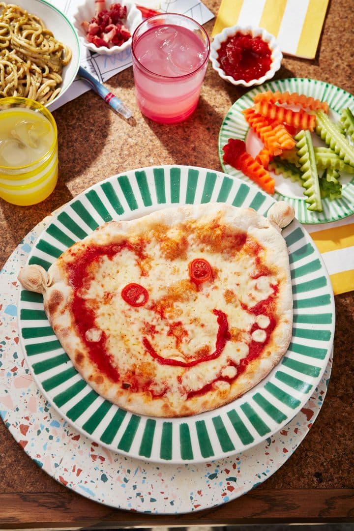 Pizza with a face made out of tomato & pepper