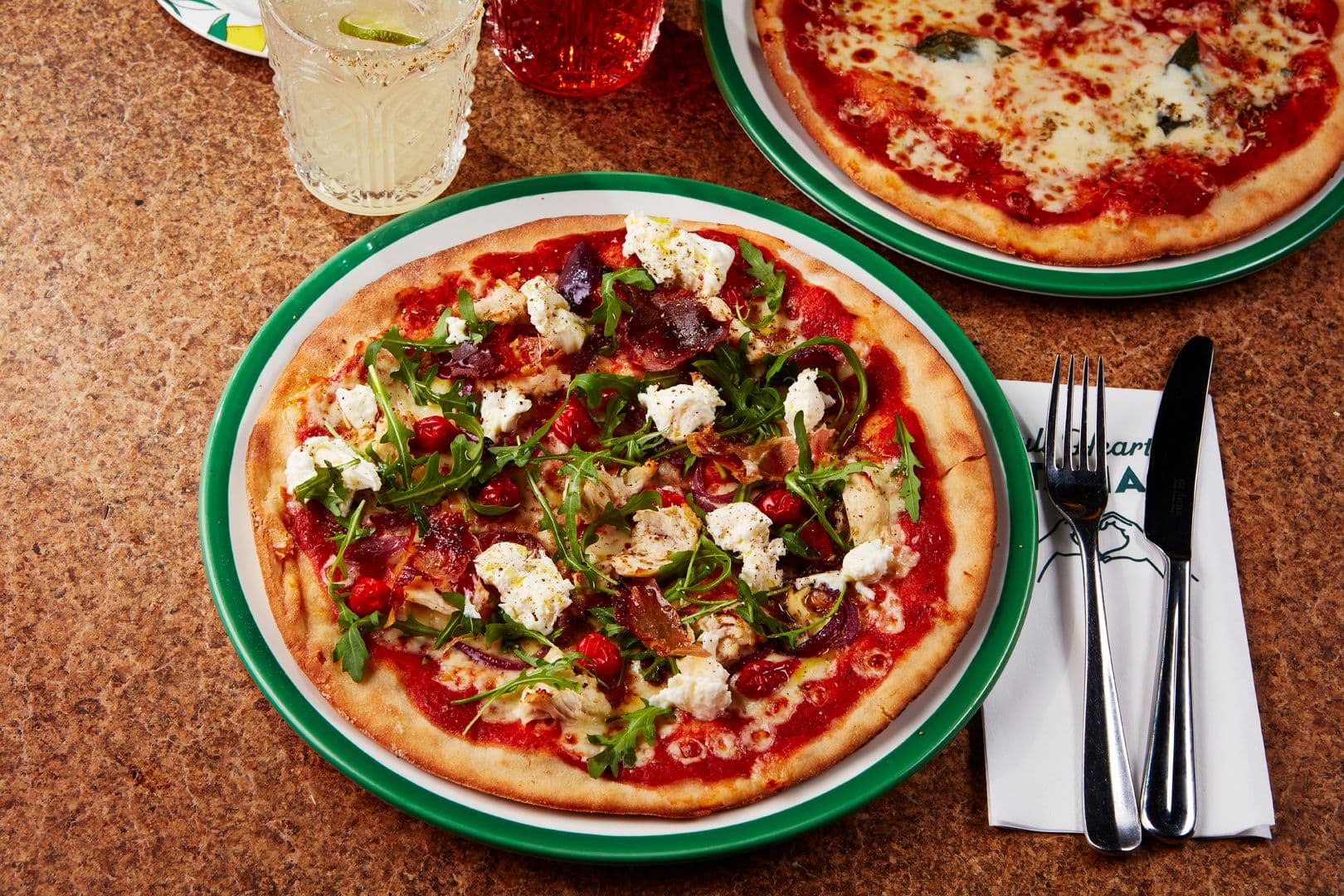 non gluten containing pizza on a table topped with rocket and chicken